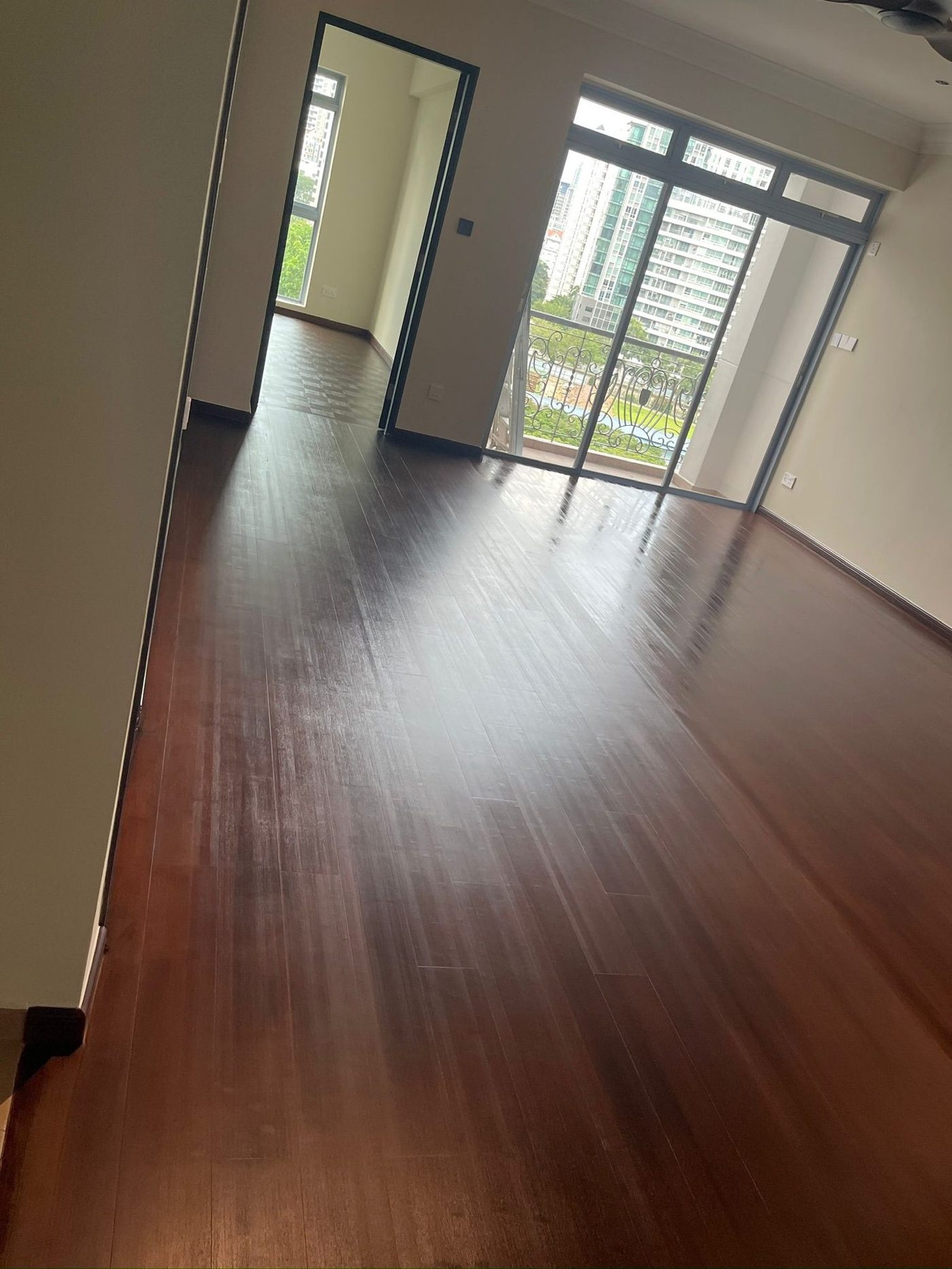 Dark-stained bamboo floor in a Singapore condominium hallway and living area, with skirting and balcony beyond
