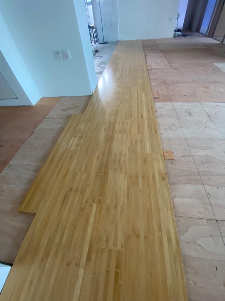 Bamboo planks being dry-laid over plywood underlay during a Singapore residential installation
