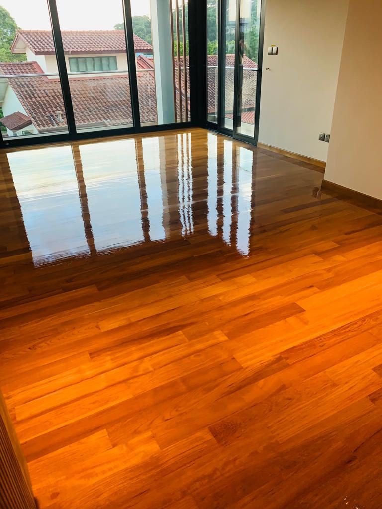 High-gloss timber wood floor in a Singapore living room reflecting daylight from large floor-to-ceiling windows